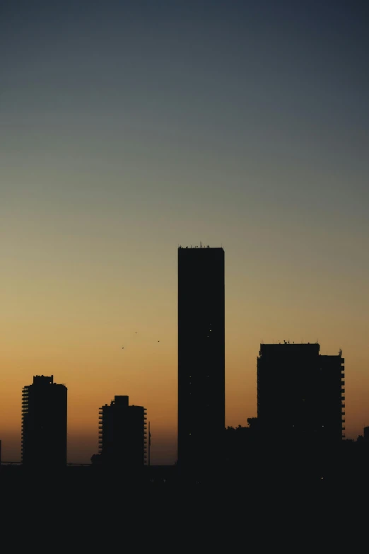 the sky is clear with silhouettes of buildings in the background