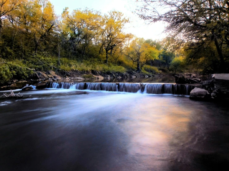 a small waterfall is running under a bright sun