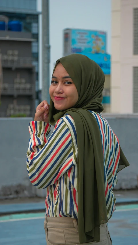 a woman with a green scarf and a hat smiles for the camera