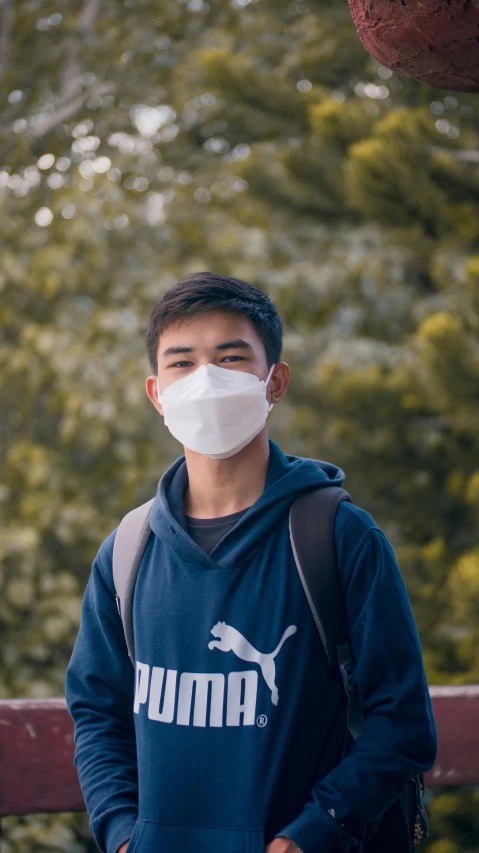 a man stands outside wearing a white face mask