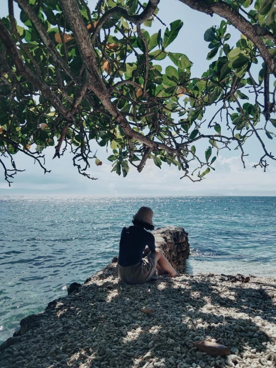 a man is sitting on the rocks overlooking the water