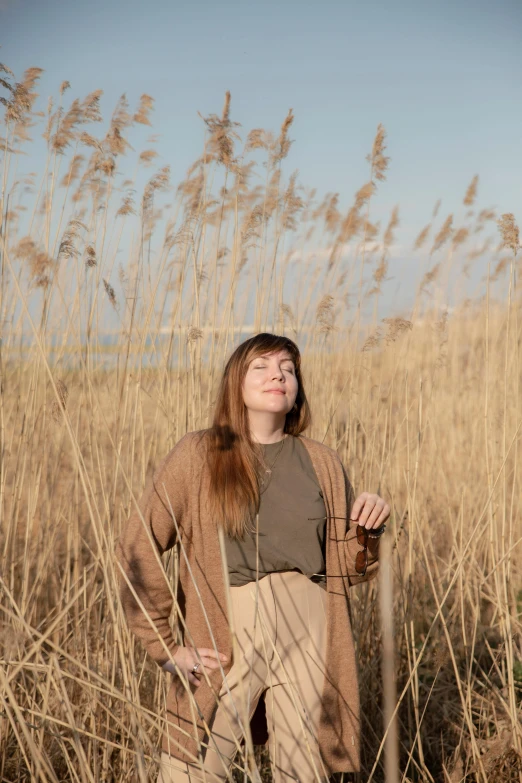 a woman in a grassy field looking up with her eyes closed