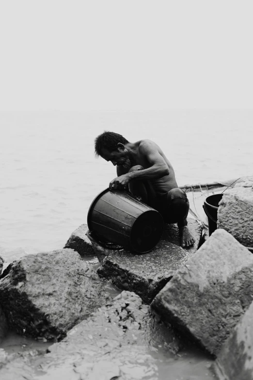 a man sitting on rocks and holding an item