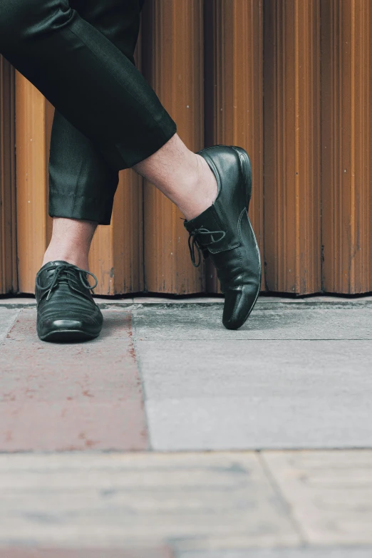 a person standing near a wall wearing black shoes