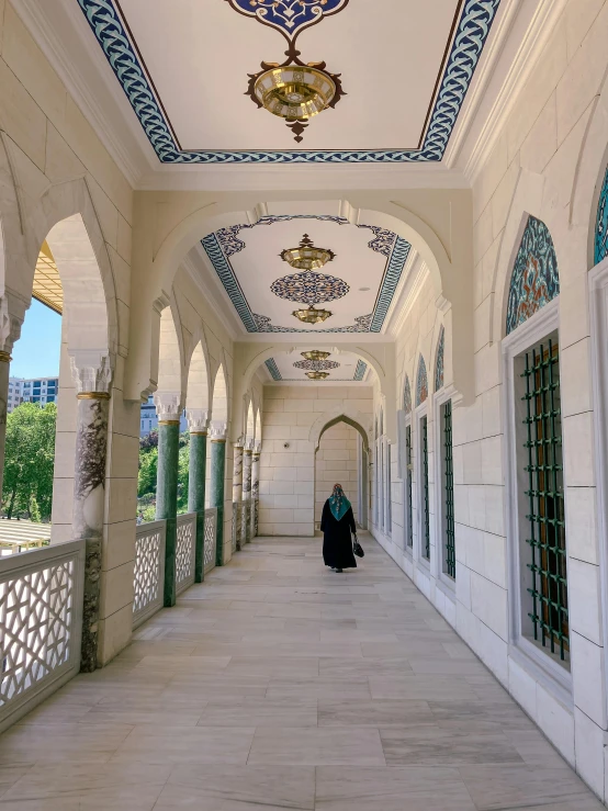 the walkway is lined with windows, chandeliers, and columns