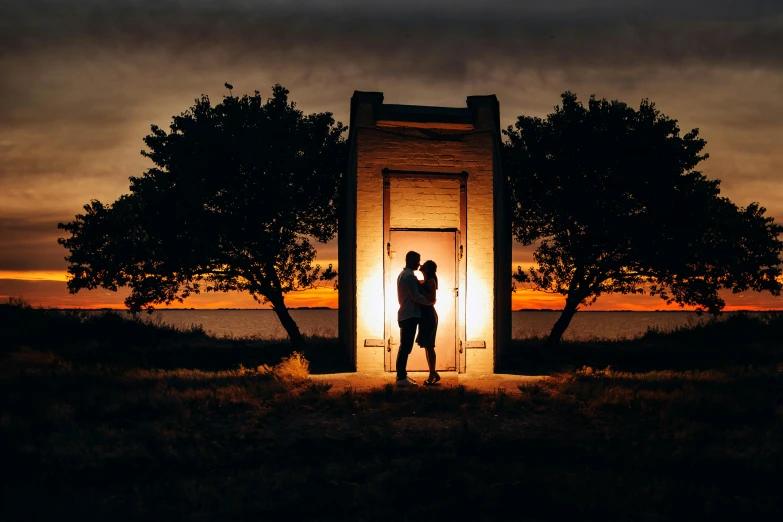 two people standing in the dark beside trees