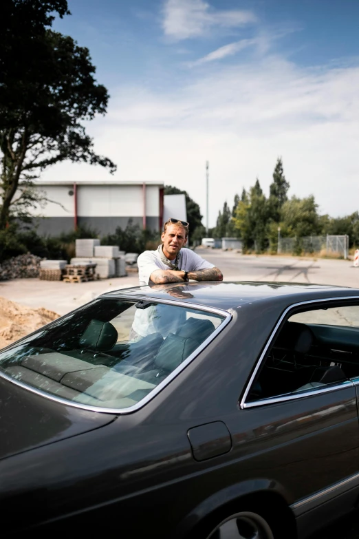 a man leaning on the hood of his car