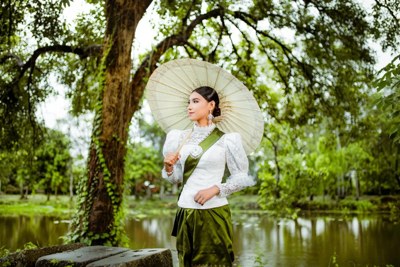 a woman standing under a tree while holding an umbrella