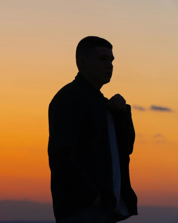 a man looking off into the distance at sunset