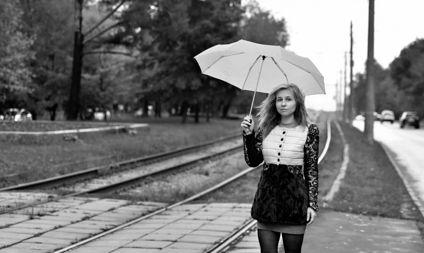 woman holding an umbrella standing on train tracks