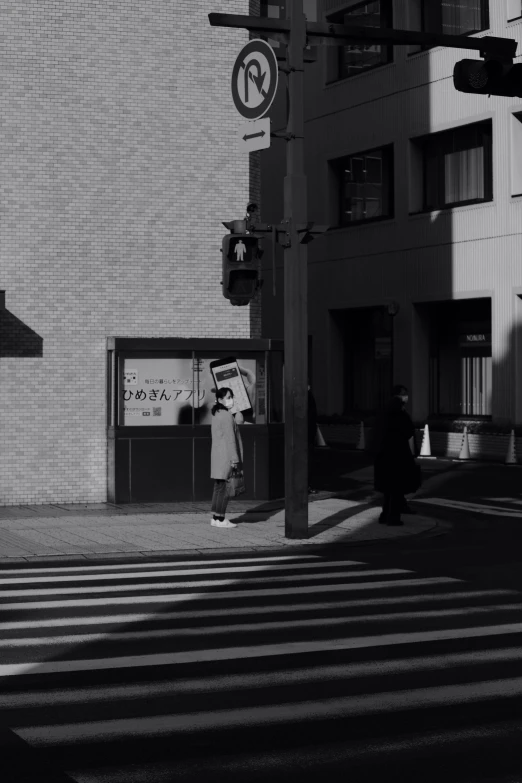 a woman standing on the corner of a crosswalk