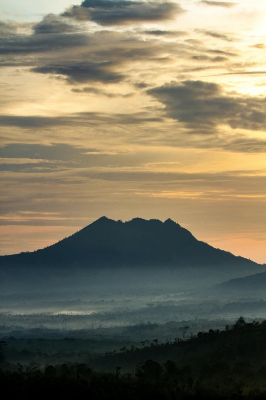 silhouetted pograph of the sun setting on a distant mountain