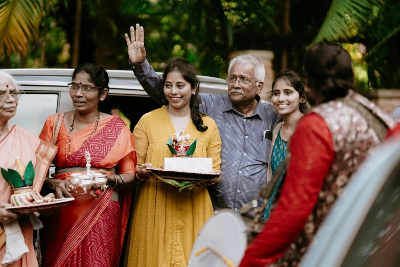 some people are standing around a car and waving