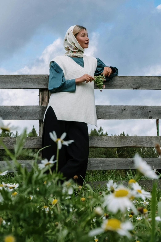 woman with a shawl over her head, standing next to fence