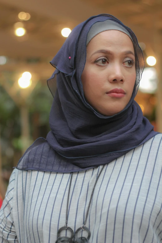 a woman in a striped shirt and veil looking ahead