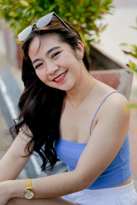 a smiling woman in a blue top and sunglasses