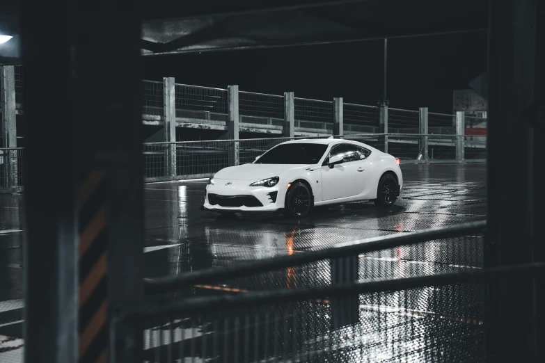 a white sports car in a parking lot on a rainy day