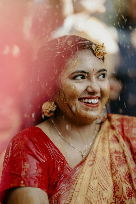 a woman smiling and covering her face with orange dust