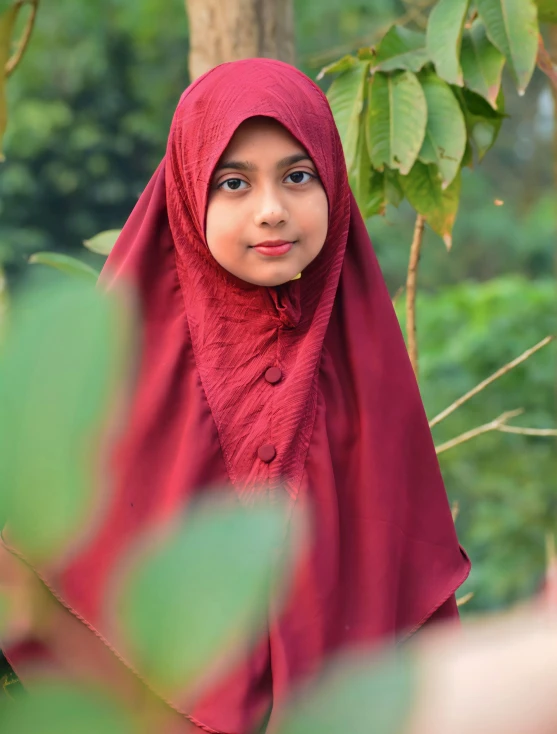 a  in a red scarf is standing next to a tree