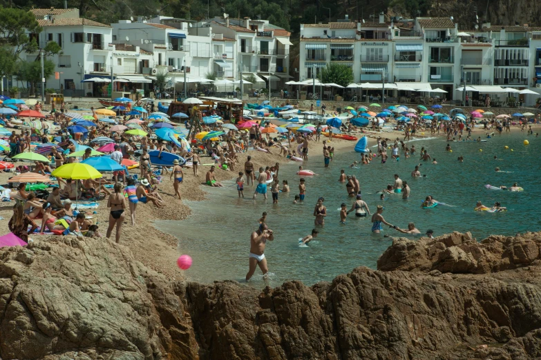 a crowded beach that has umbrellas all over it