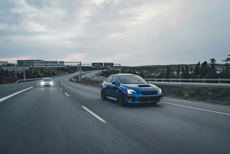 two cars driving down the road on a cloudy day