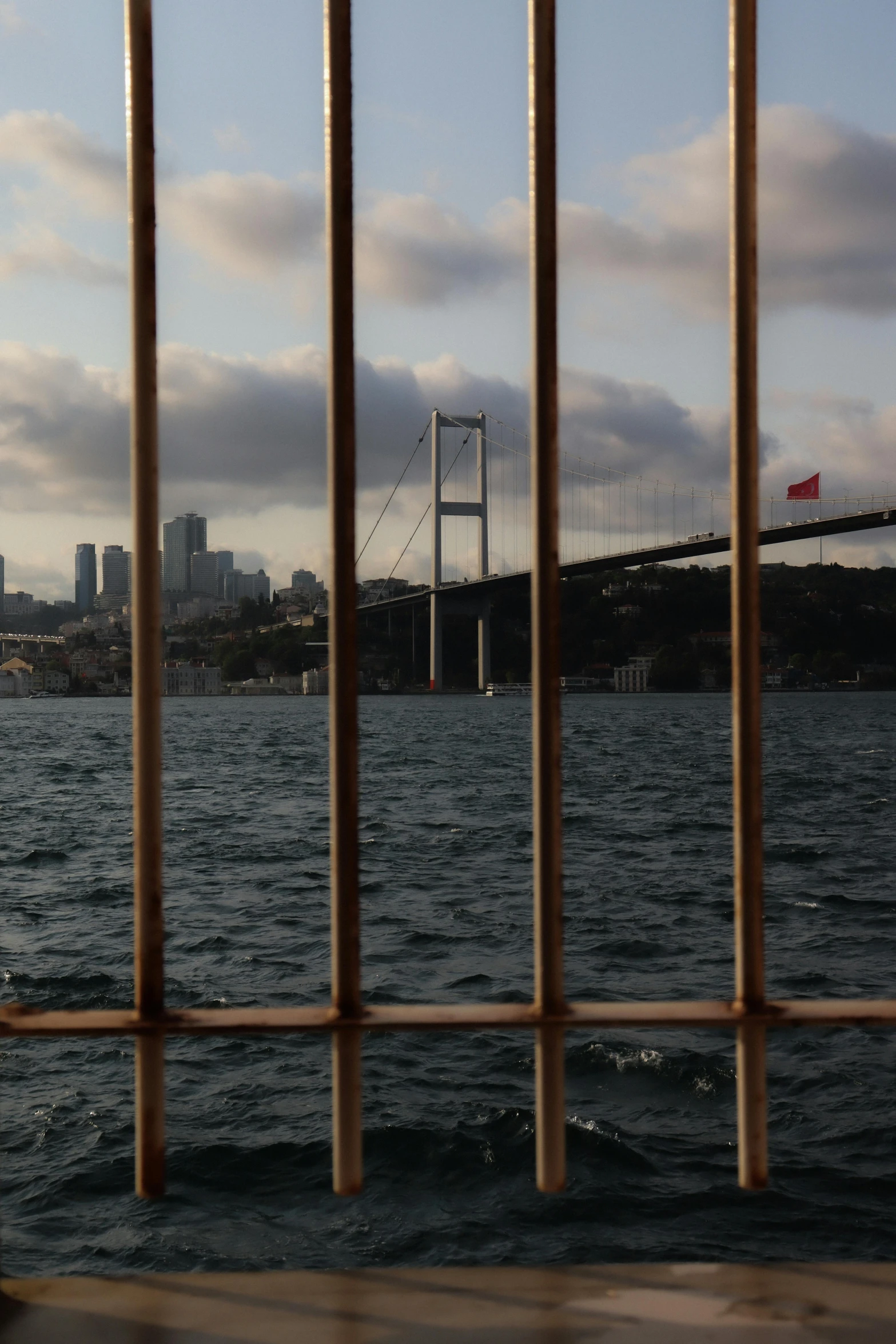 an open gate in front of a body of water with a bridge in the distance