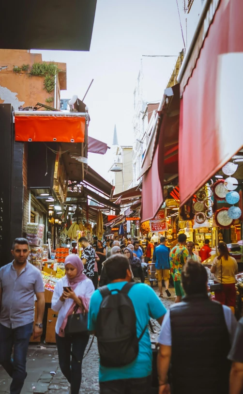 several people walking around a market with many shops