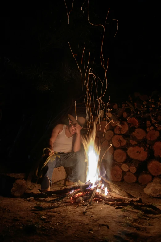 a man sits in front of the fire, as he looks at soing