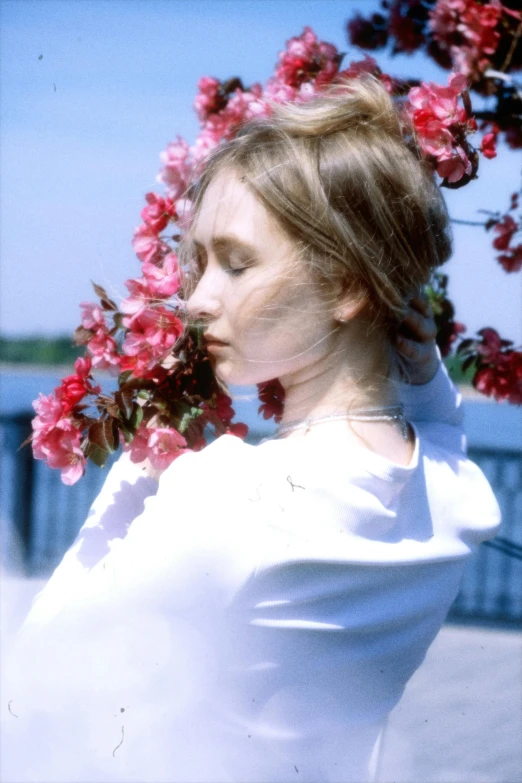 a woman is standing outside near a large flower bush