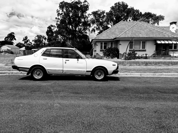 a white car parked outside of a house in the street