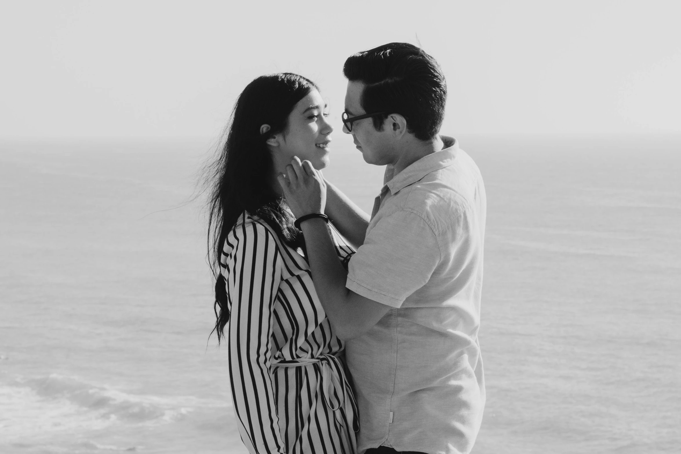 a man and a woman facing each other on a beach