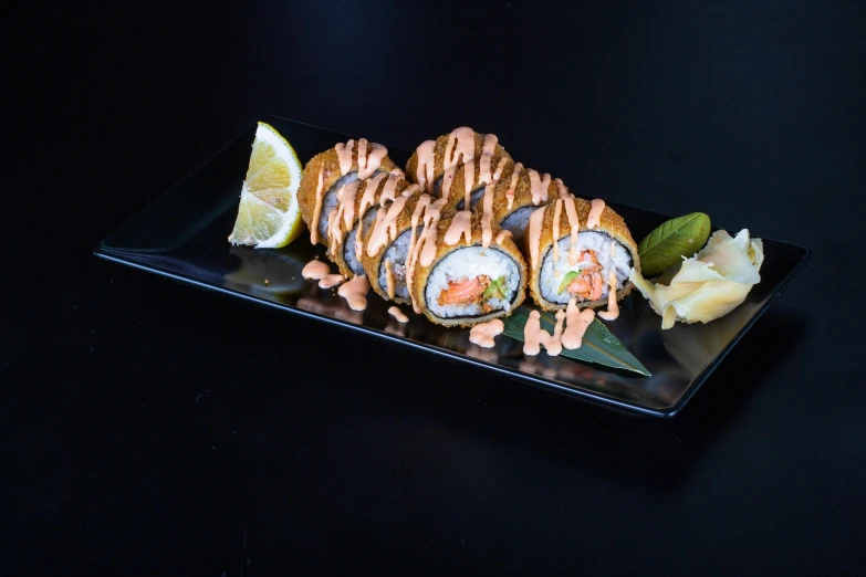 a black tray with different types of sushi and a lime