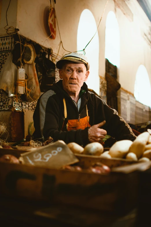 an older man sits at his counter filled with eggs