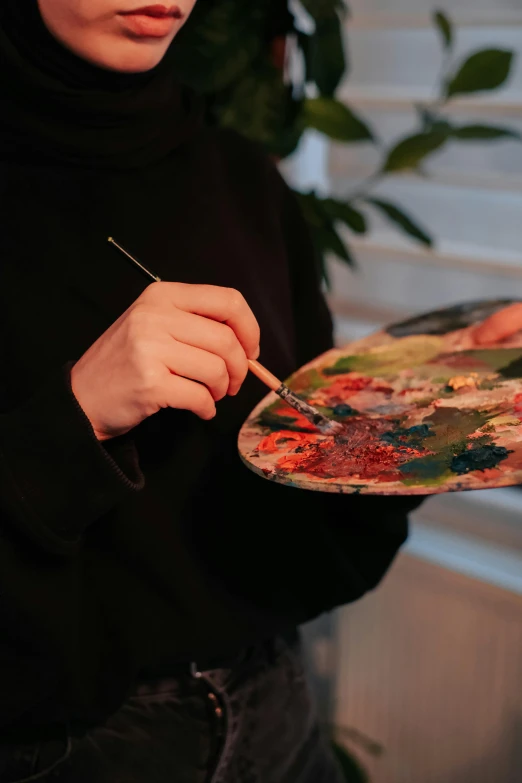 a young woman painting on a canvas with a paintbrush