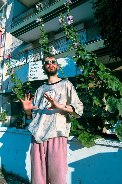 a man holding his hand out to stop a hanging flower plant