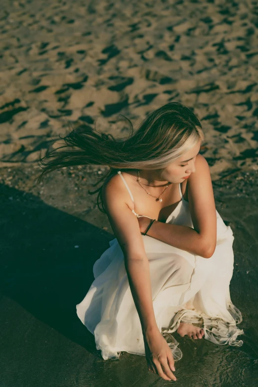 a woman kneeling down to sit down in the sand