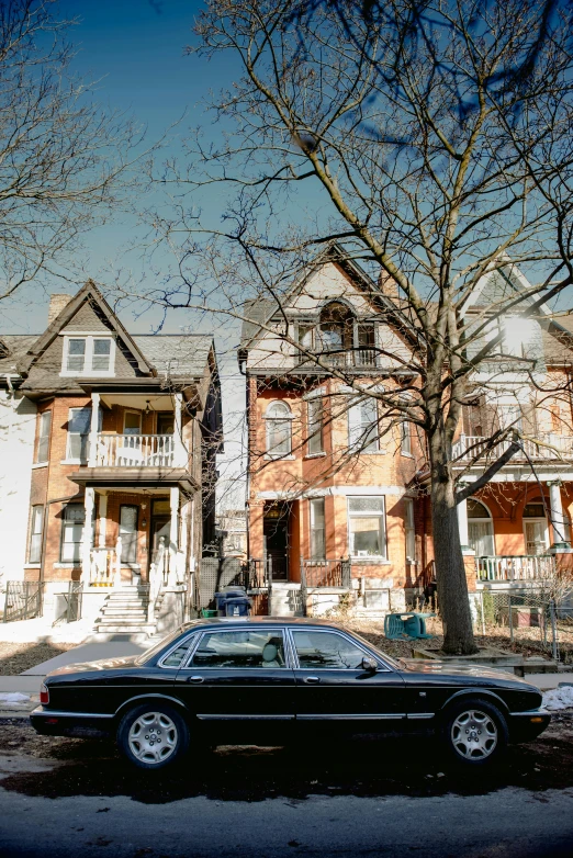 a black car parked in front of two large brick houses