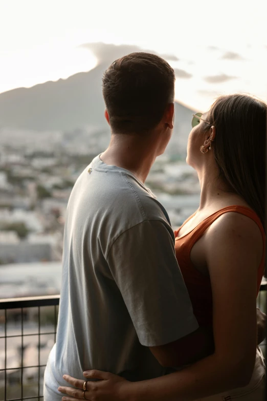 a couple standing in front of a mountain at sunset