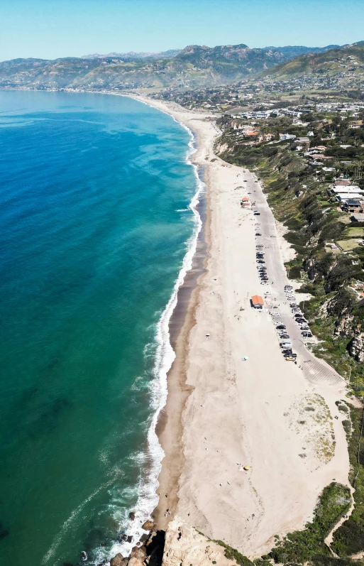 an aerial view of a long beach with houses and water