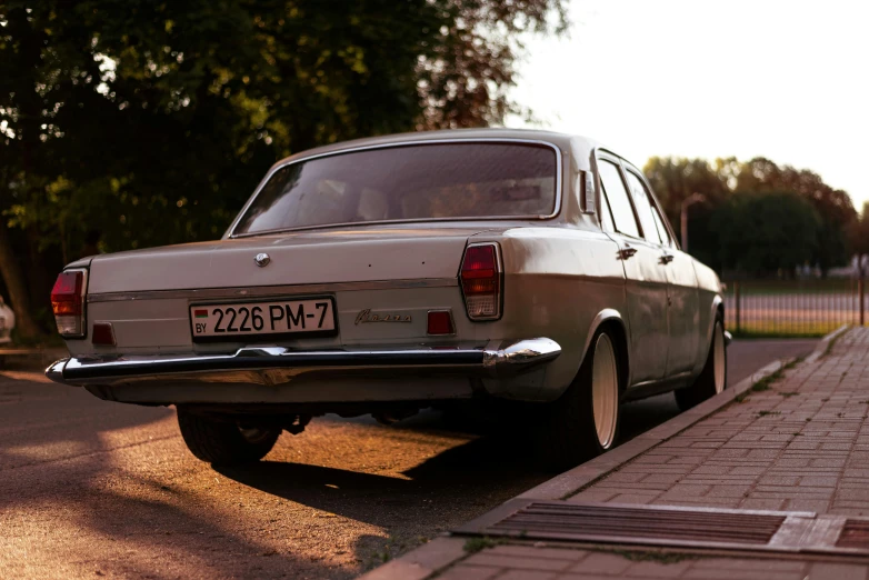 a car is parked on a brick sidewalk next to trees