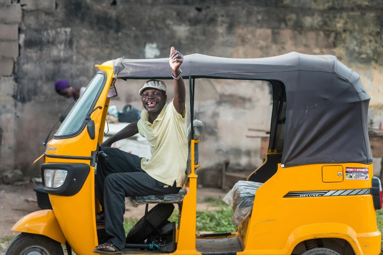 man in a yellow tuk drives a small, three - wheeled vehicle