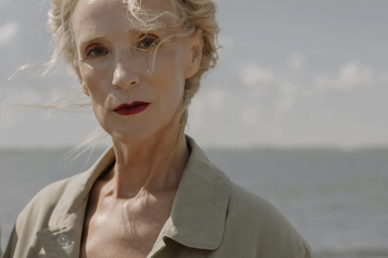 an older woman is posing in front of the ocean