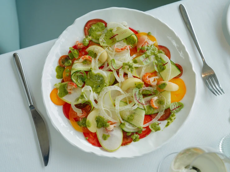 a white plate with a salad on it and utensils