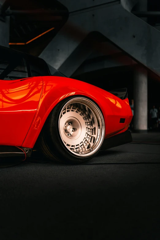 an old red car in the dark with chrome rims