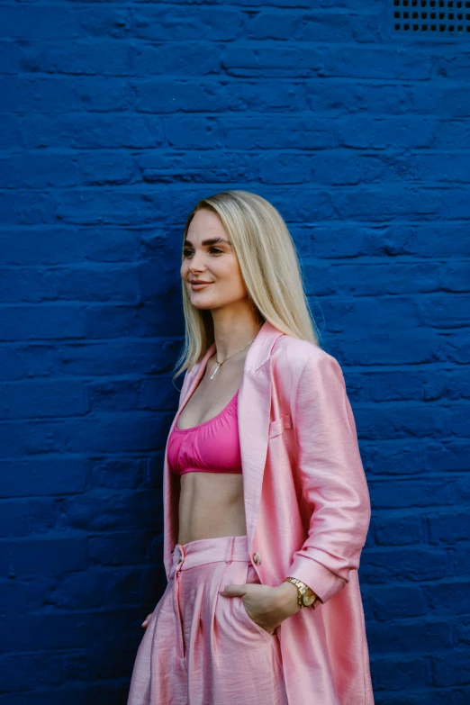 a woman is standing near a blue brick wall