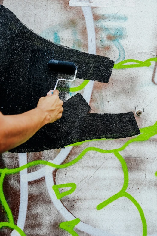 someone using a brush to paint graffiti on a piece of concrete