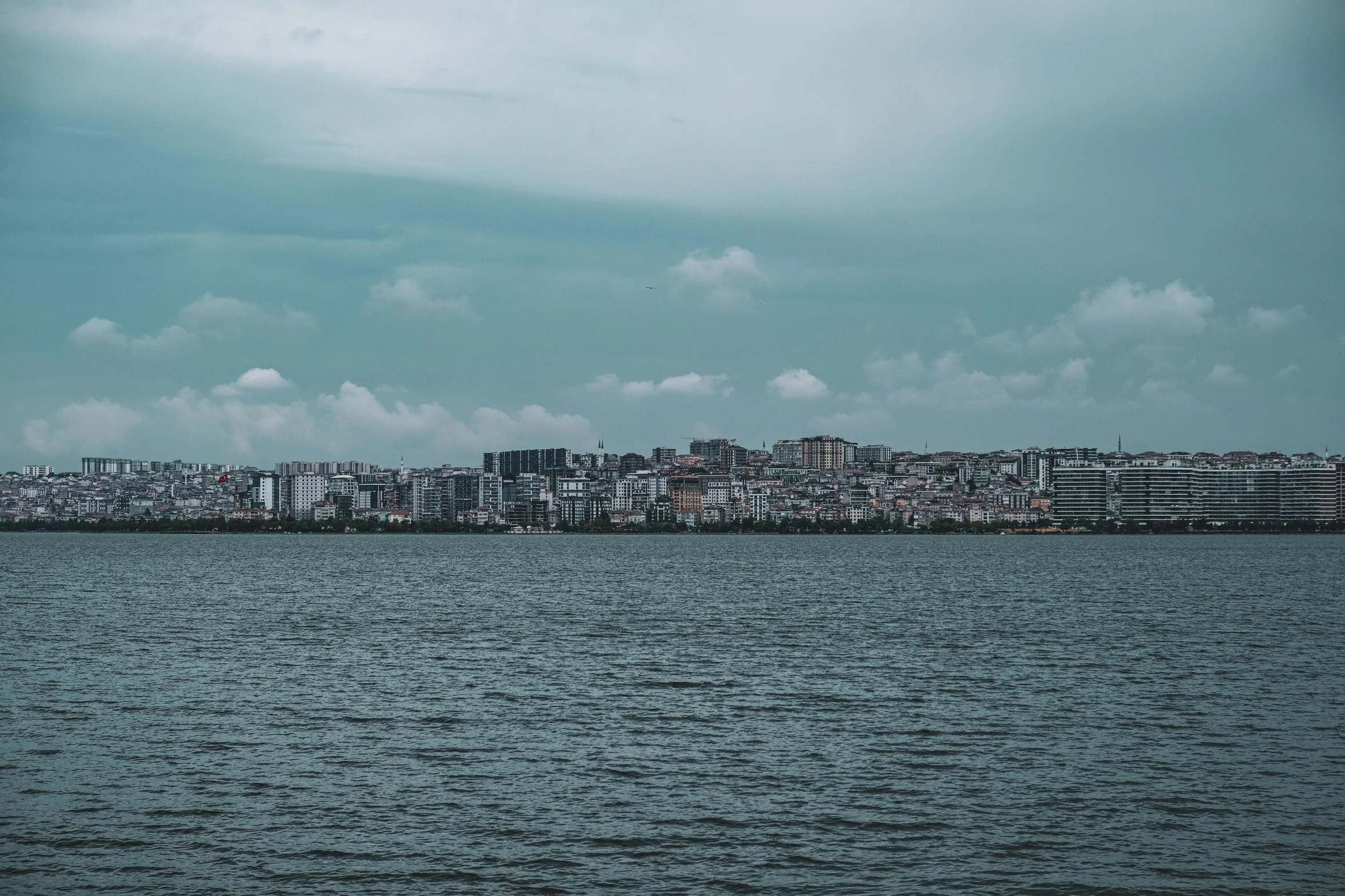 a skyline seen from the water with some clouds