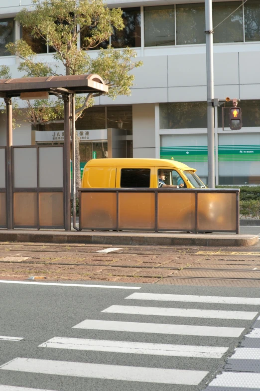 yellow van stopped at the side of the road in front of a shelter