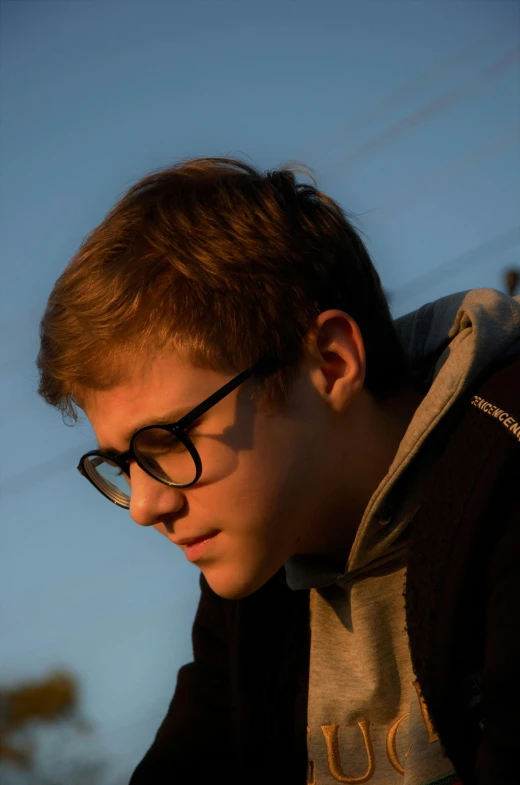 a young man in glasses is looking down