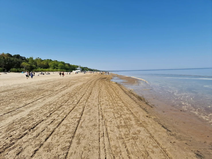 people are walking along the beach next to the ocean